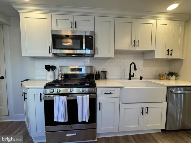 a kitchen with white cabinets and black appliances