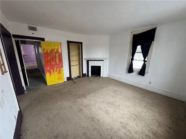 an empty room with fireplace and windows