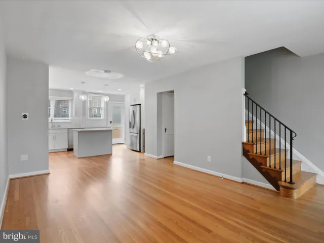 a view of a hallway with wooden floor and a kitchen