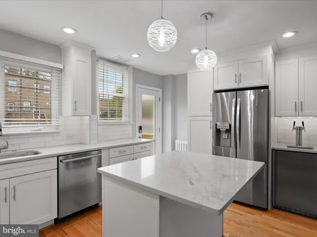 a kitchen with stainless steel appliances granite countertop a sink a stove a refrigerator and island with wooden floor