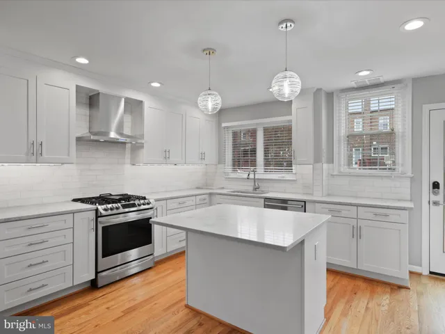 a kitchen with a stove and a kitchen island with wooden floor