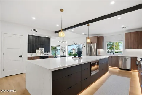 a kitchen with stainless steel appliances a sink and a stove top oven with wooden floor