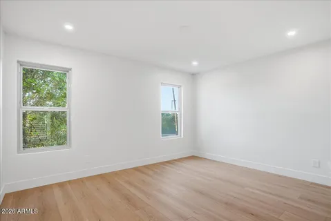 an empty room with wooden floor and windows
