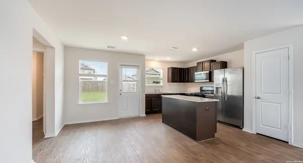 a kitchen with stainless steel appliances granite countertop a refrigerator a sink a stove and white cabinets with wooden floor