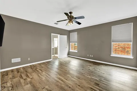 a view of an empty room with window and wooden floor