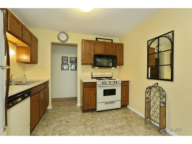 1549 Sandhurst Court, Unit B Wheaton, IL 60189 - Photo 4 of 11 a kitchen with stainless steel appliances a stove and a microwave