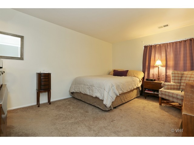 1549 Sandhurst Court, Unit B Wheaton, IL 60189 - Photo 7 of 11 a bedroom with a bed and a couch