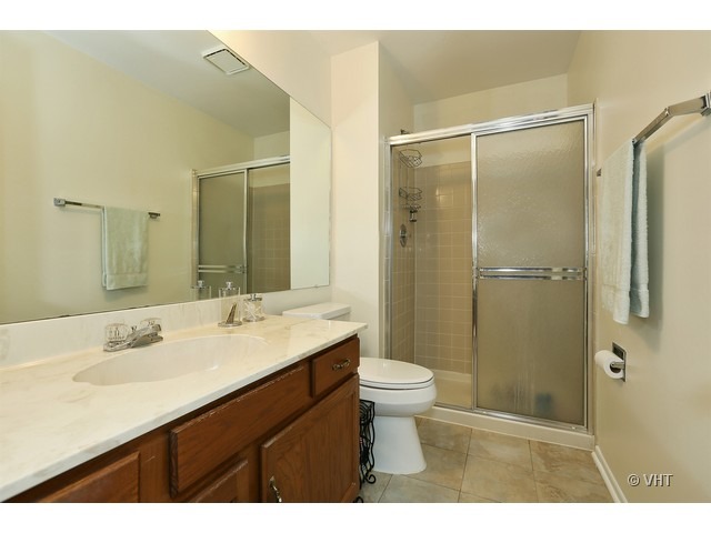 1549 Sandhurst Court, Unit B Wheaton, IL 60189 - Photo 9 of 11 a bathroom with a sink a toilet a shower and a mirror
