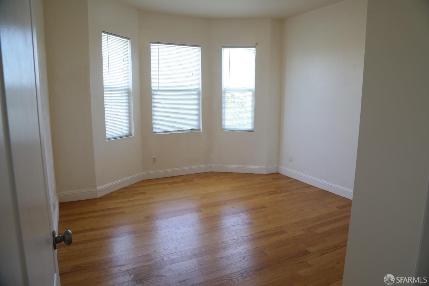 2726 San Bruno Avenue, Unit 2724 San Francisco, CA 94134 - Photo 8 of 13 an empty room with wooden floor and windows