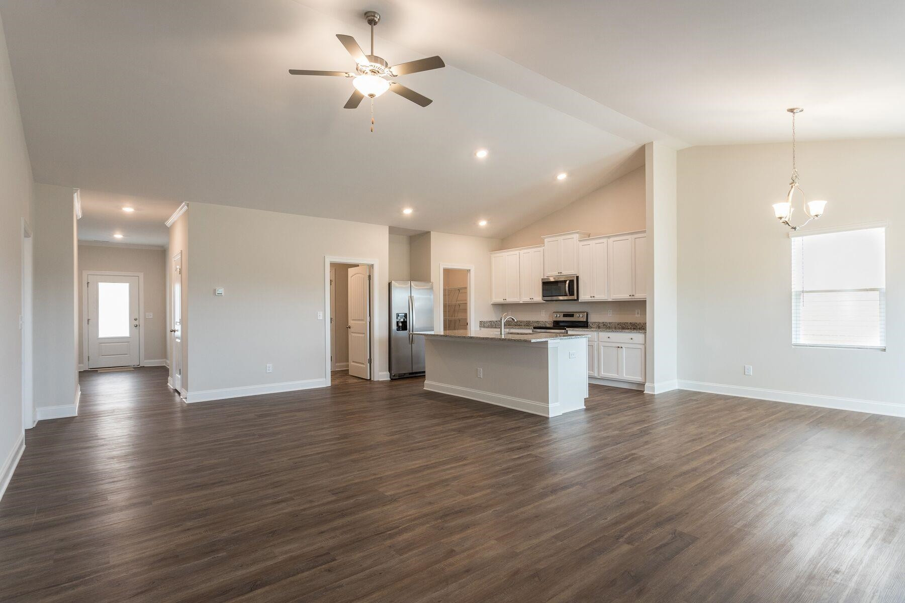 40 Symmetry Loop Youngsville, NC 27596 - Photo 4 of 17 a view of an empty room and kitchen with wooden floor