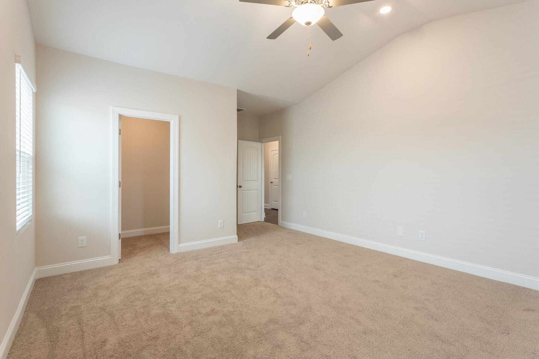40 Symmetry Loop Youngsville, NC 27596 - Photo 10 of 17 an empty room with a chandelier fan and windows