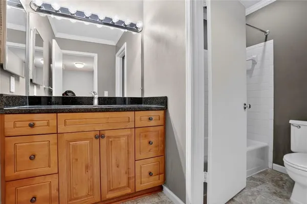 a bathroom with a granite countertop sink a toilet and a mirror