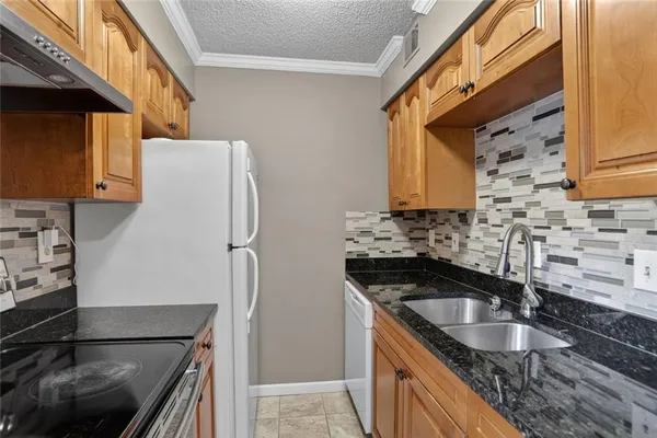 a kitchen with granite countertop a refrigerator and a sink