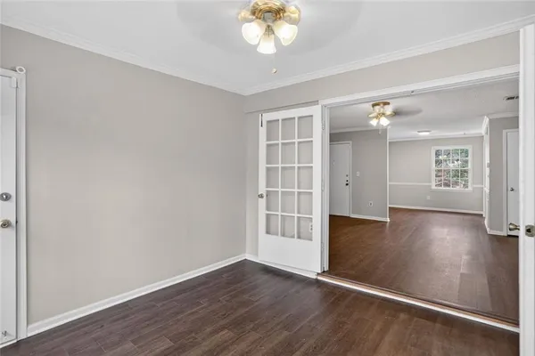 an empty room with wooden floor chandelier and windows