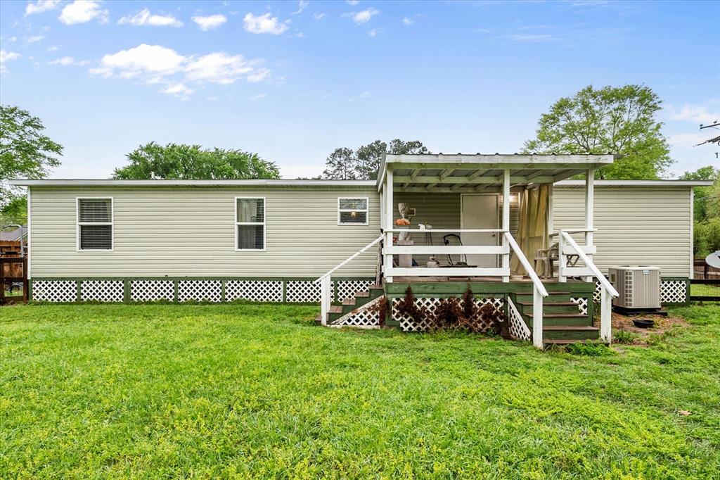 14036 Old Texaco Road Conroe, TX 77302 - Photo 24 of 40 Rear view of house with cooling unit, a wooden deck, and a yard