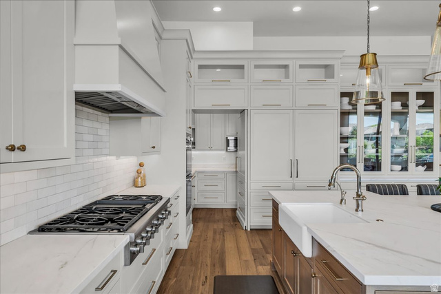 2608 Canyon Ridge Drive St. George, UT 84770 - Photo 22 of 86 Gourmet kitchen with professional-grade gas range, full-height subway tile backsplash, white shaker cabinetry, integrated refrigerator, and a kitchen island featuring a farmhouse sink and polished chrome faucet