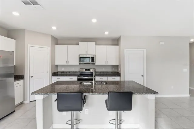 a kitchen with stainless steel appliances granite countertop a stove a refrigerator a sink a counter top space and cabinets