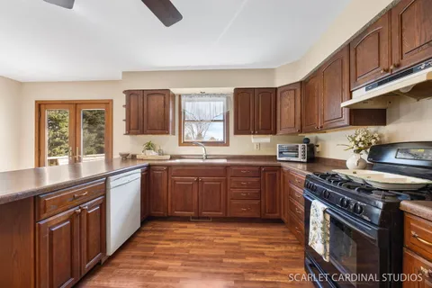 a kitchen with stainless steel appliances granite countertop a stove a sink dishwasher and a microwave oven with wooden cabinets