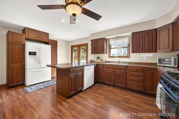 a kitchen with stainless steel appliances granite countertop a refrigerator a sink dishwasher a stove and white countertops with wooden floor