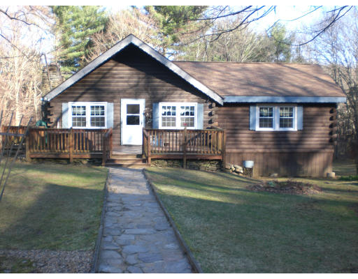 a front view of house with yard and trees in the background