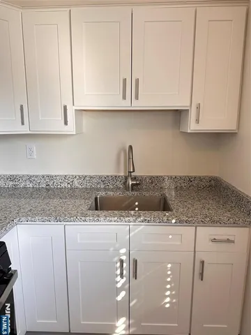 a kitchen with granite countertop white cabinets and a sink
