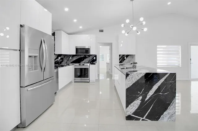 a kitchen with kitchen island a counter top space stainless steel appliances and a window