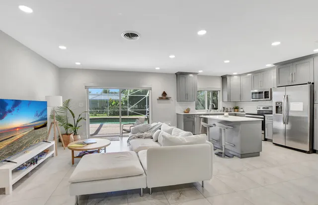 a living room with stainless steel appliances furniture and a flat screen tv