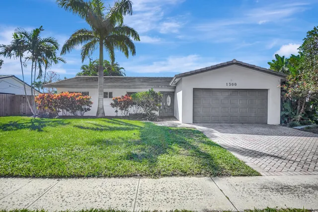 front view of house with a yard and palm trees