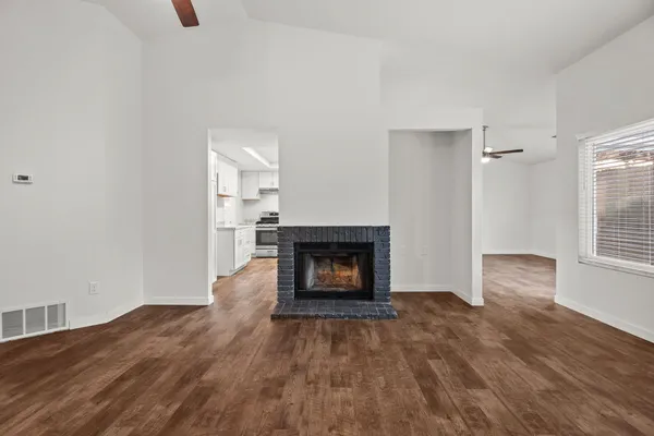 an empty room with wooden floor fireplace and window