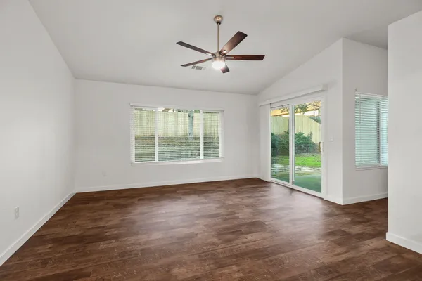 a view of an empty room with wooden floor and a window