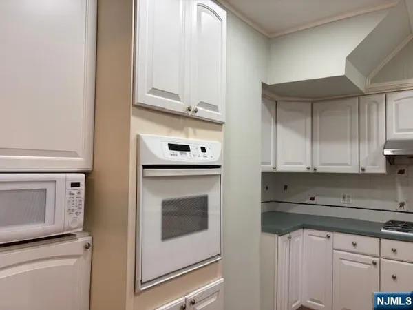 a kitchen with granite countertop white cabinets and stainless steel appliances
