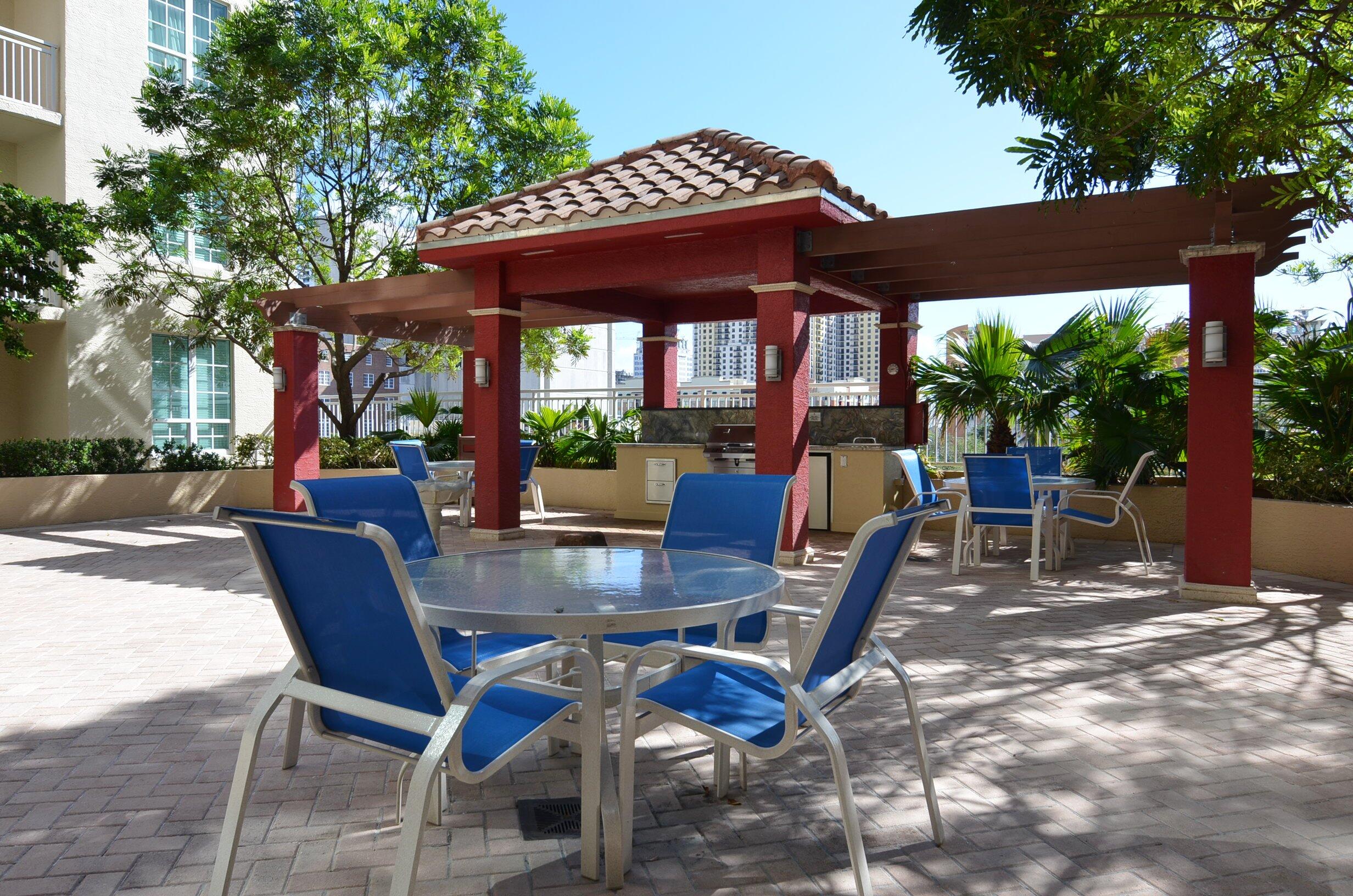 410 Evernia Street, Unit 519 West Palm Beach, FL 33401 - Photo 26 of 27 a view of patio with table and chairs potted plants and a large tree