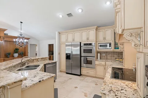 a kitchen with stainless steel appliances kitchen island granite countertop a sink refrigerator and cabinets