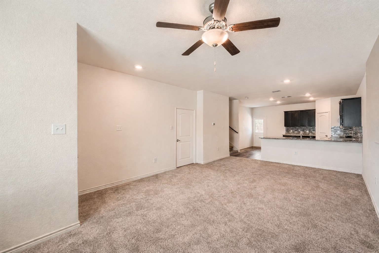 14513 Prairie Sod Lane Elgin, TX 78621 - Photo 5 of 36 an empty room with a kitchen and a ceiling fan