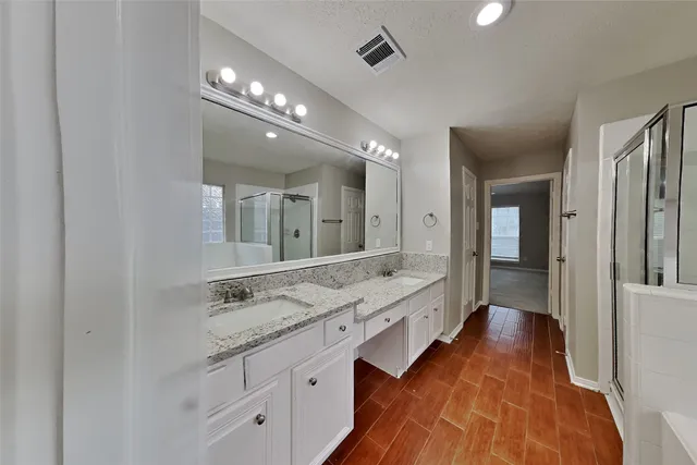 a spacious bathroom with a granite countertop double vanity sink and a mirror