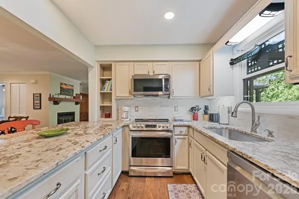 a kitchen with granite countertop stainless steel appliances a sink stove and cabinets
