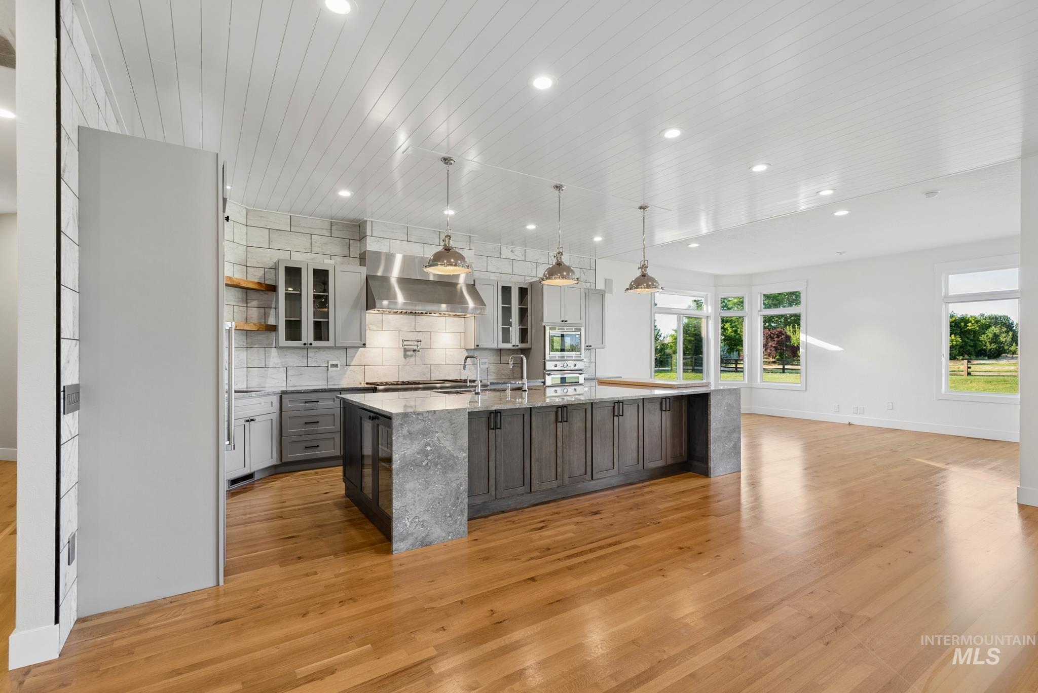 2050 Artesian Road Eagle, ID 83616 - Photo 9 of 49 Hardwood flooring extends throughout this expansive room, featuring a built-in media center with shelving, white cabinetry, and a fireplace