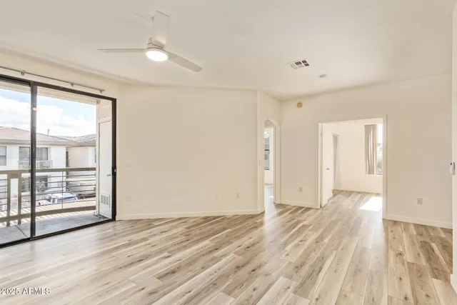 an empty room with wooden floor and windows