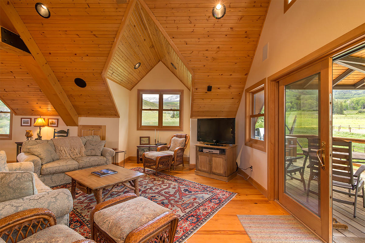 3520 County 58P Road Placerville, CO 81430 - Photo 29 of 76 a living room with furniture a flat screen tv and a floor to ceiling window
