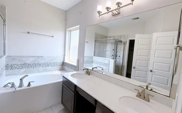 a bathroom with a tub sink double vanity granite and shower