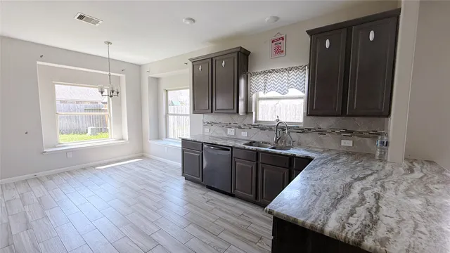 a kitchen with granite countertop wooden floors wooden cabinets a sink and a window