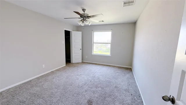 an empty room with windows and fan