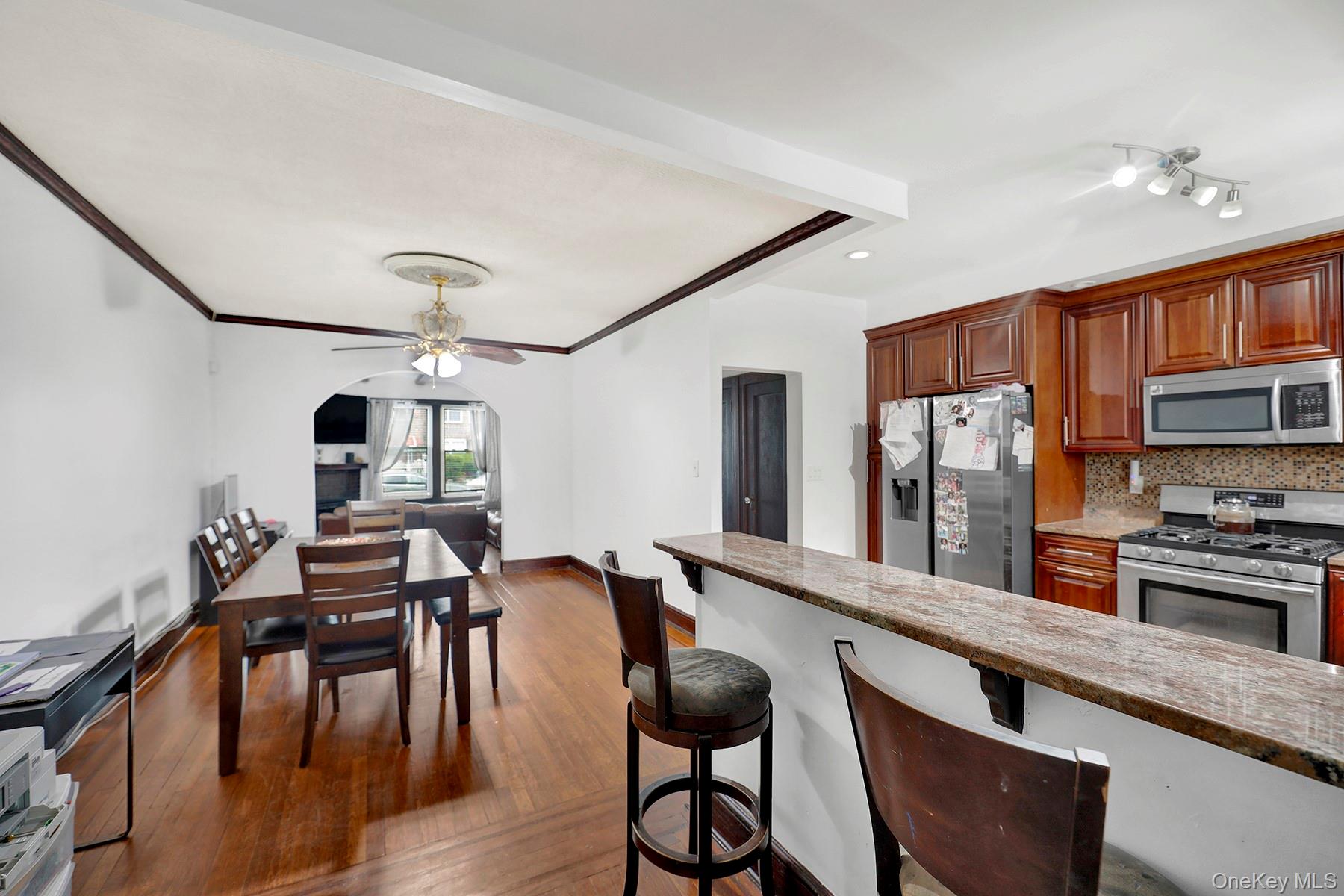 179-50 Anderson Road Queens, NY 11434 - Photo 11 of 23 Kitchen with stainless steel appliances, a ceiling fan, dark wood-style flooring, decorative backsplash, and a breakfast bar area