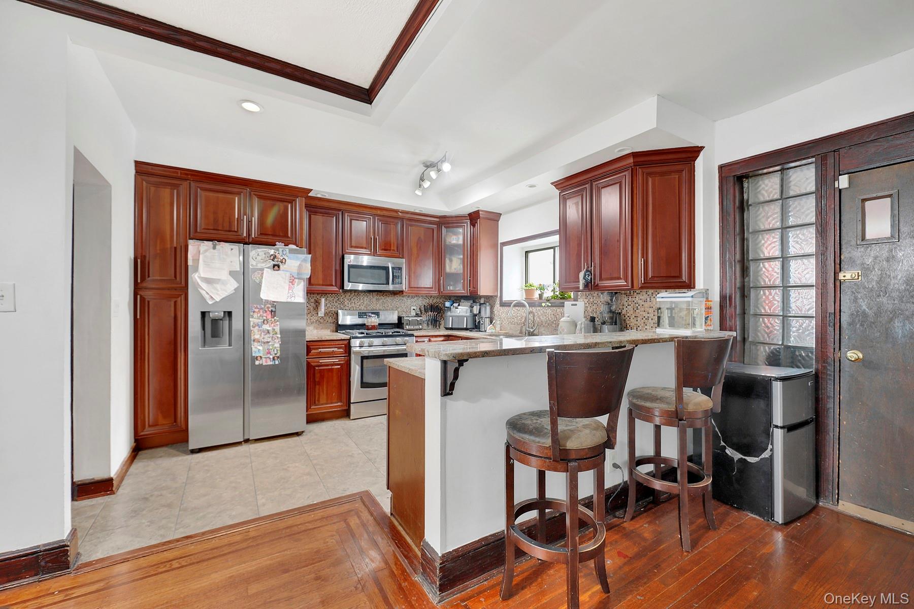 179-50 Anderson Road Queens, NY 11434 - Photo 15 of 23 Kitchen featuring stainless steel appliances, decorative backsplash, a peninsula, a breakfast bar area, and light wood-type flooring