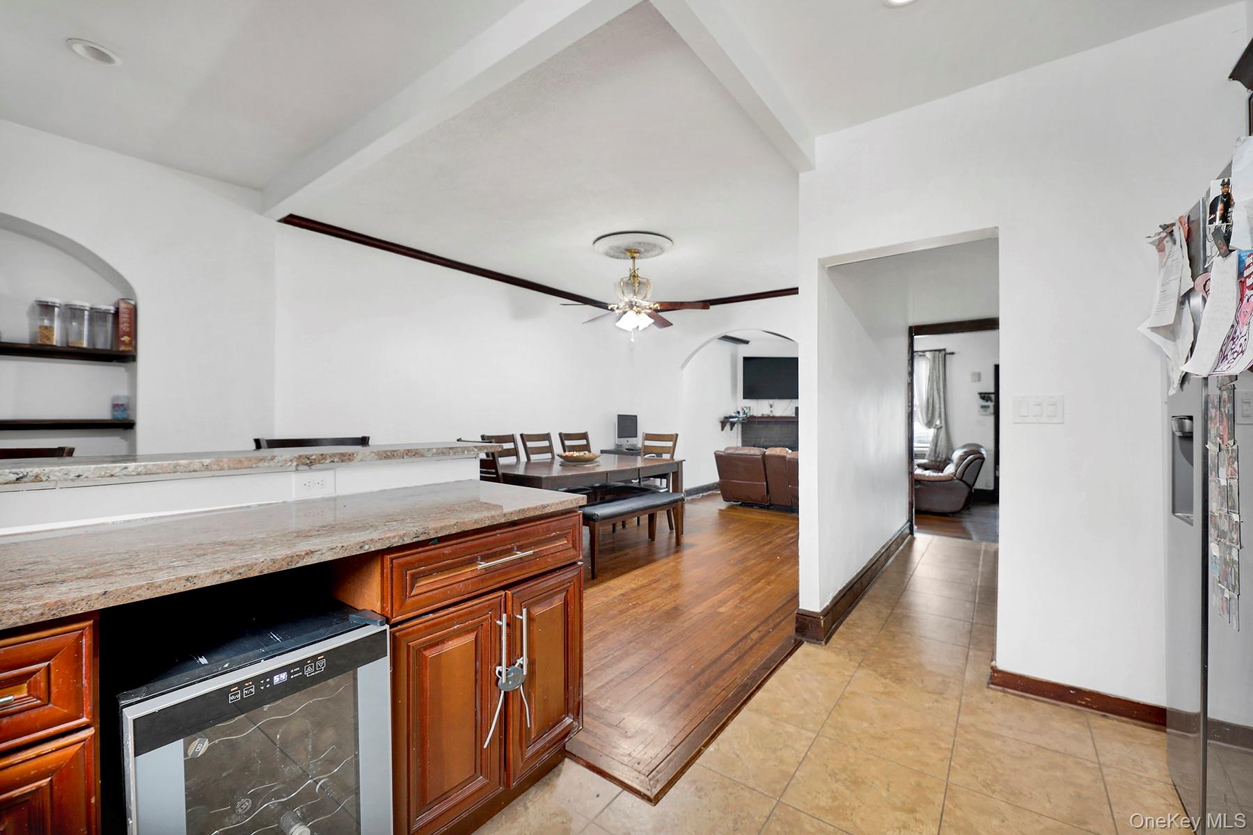 179-50 Anderson Road Queens, NY 11434 - Photo 17 of 23 Kitchen with arched walkways, ceiling fan, light tile patterned floors, beverage cooler, and brown cabinets