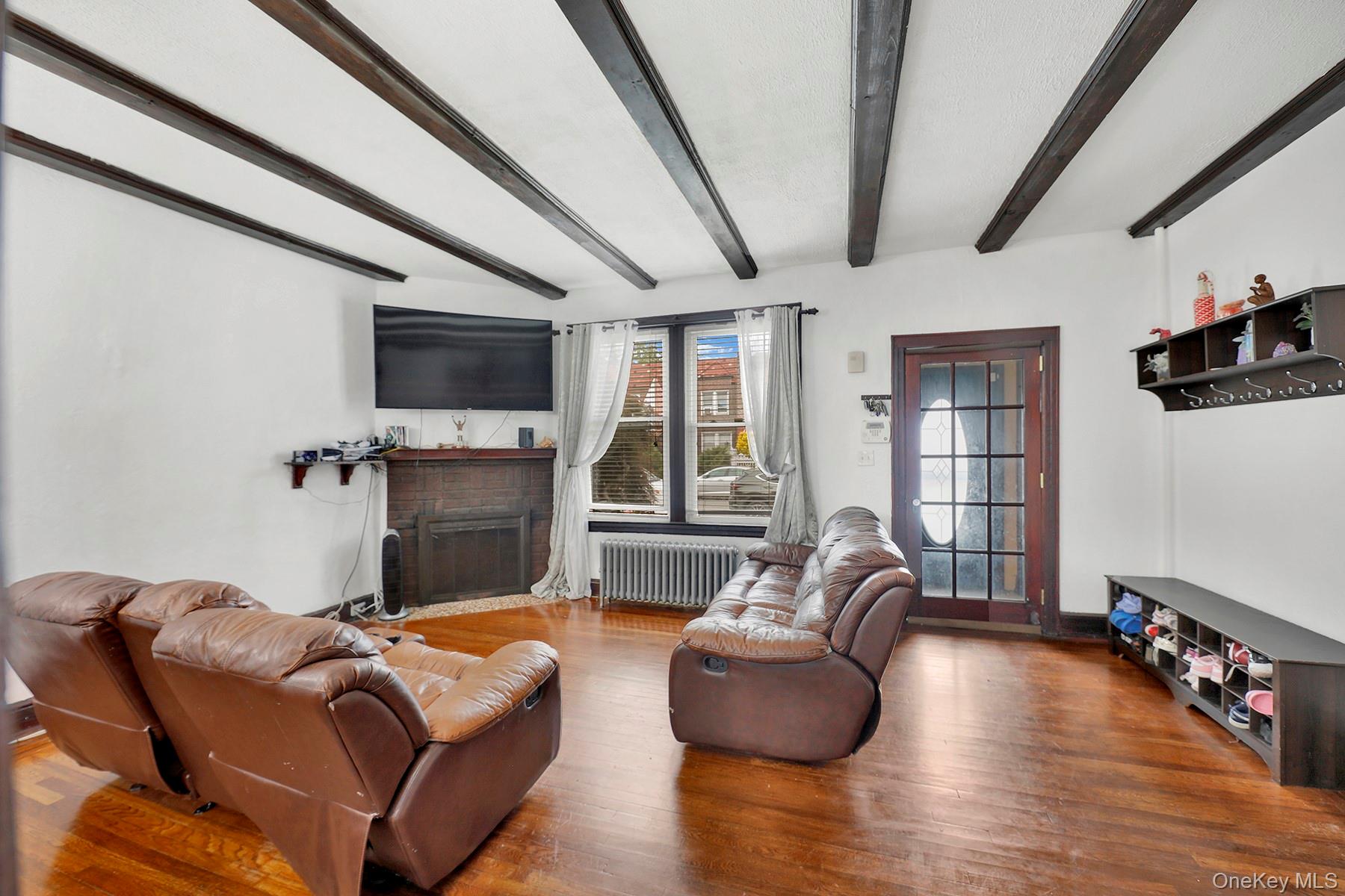 179-50 Anderson Road Queens, NY 11434 - Photo 3 of 23 Living area with radiator heating unit, beamed ceiling, a brick fireplace, and wood finished floors
