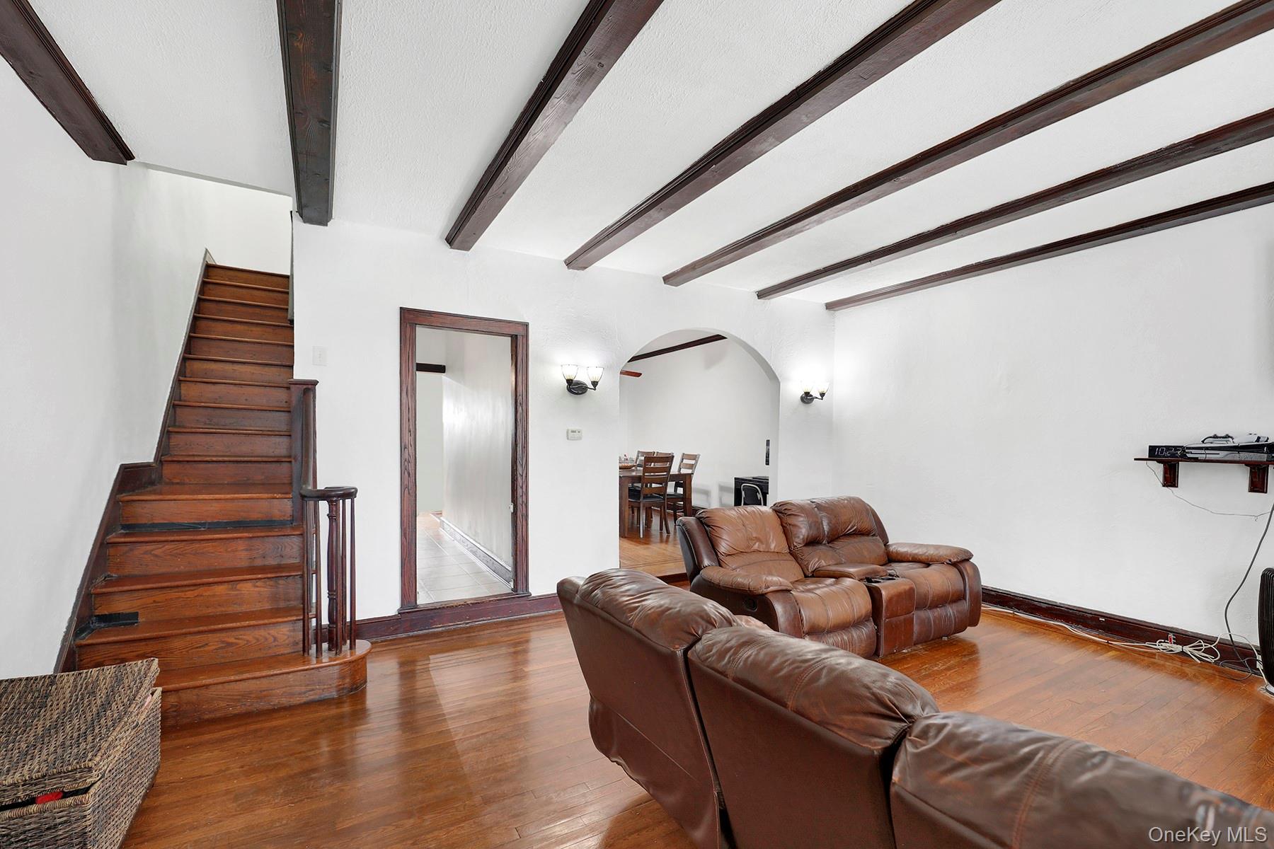 179-50 Anderson Road Queens, NY 11434 - Photo 4 of 23 Living area featuring arched walkways, beamed ceiling, wood finished floors, and stairway