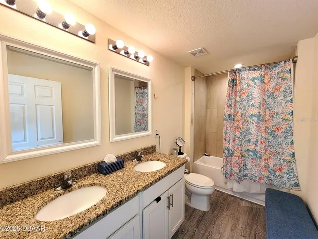 a bathroom with a granite countertop sink toilet a mirror a shower and a bathtub