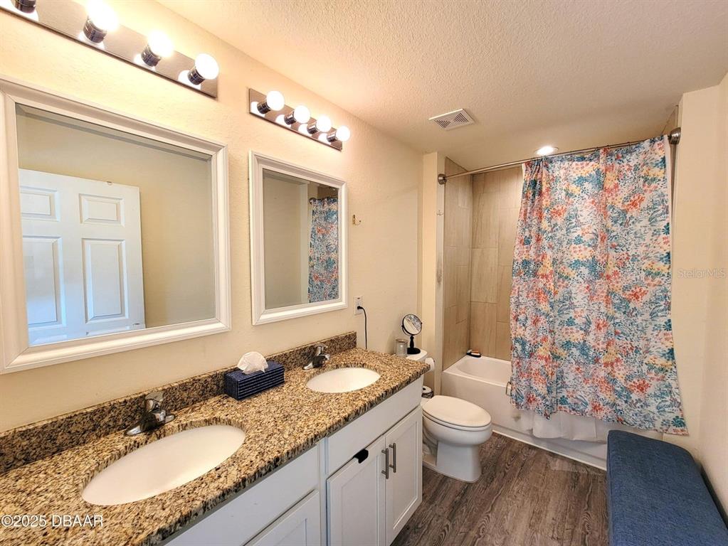 5023 Littlefield Road LaBelle, FL 33935 - Photo 19 of 36 a bathroom with a granite countertop sink toilet a mirror a shower and a bathtub