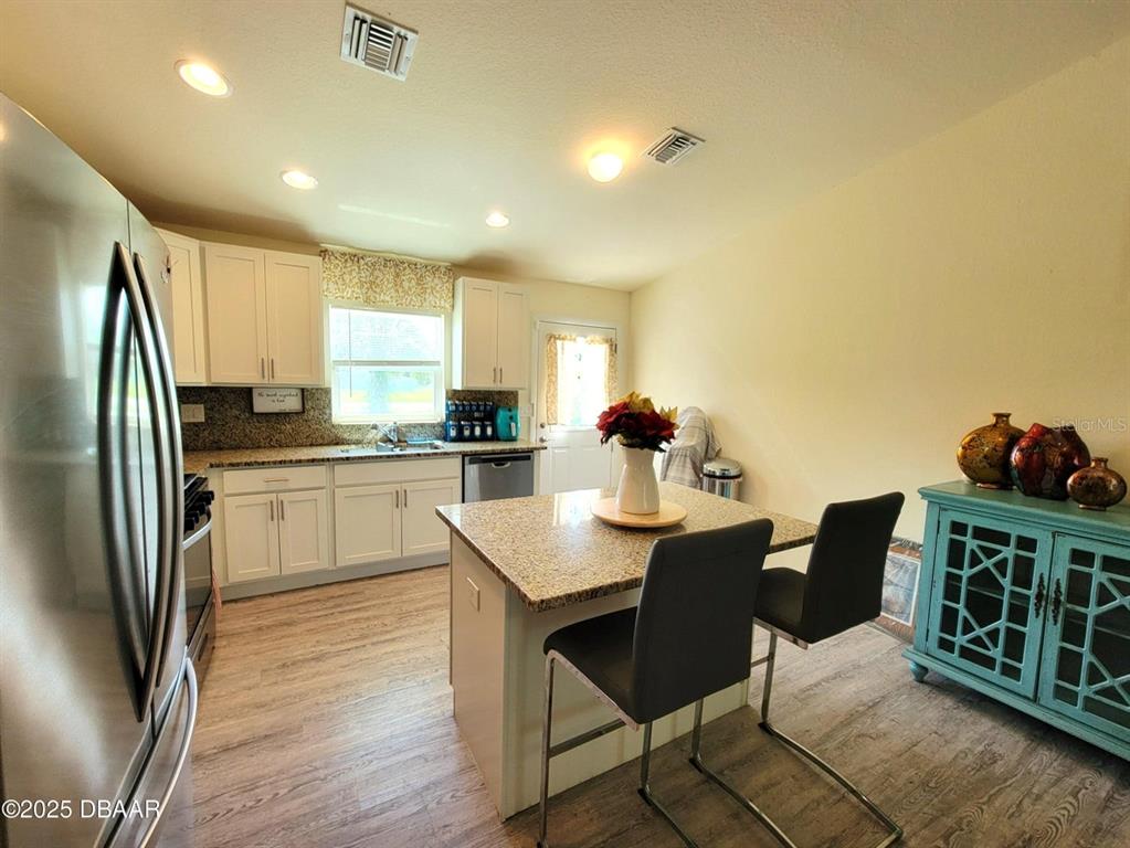 5023 Littlefield Road LaBelle, FL 33935 - Photo 6 of 36 a kitchen with stainless steel appliances granite countertop a refrigerator a stove a sink dishwasher with a dining table and chairs